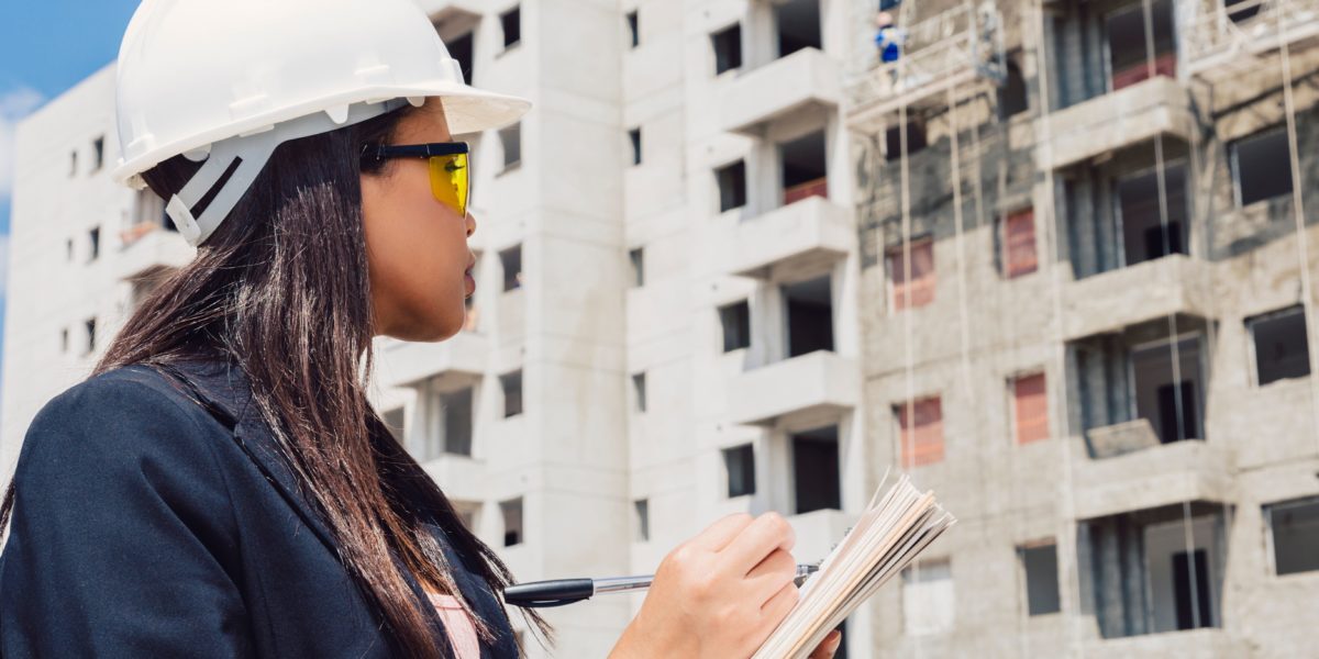 Dream Legacy Foundation - African-American woman in safety helmet writing on notepad near a building construction