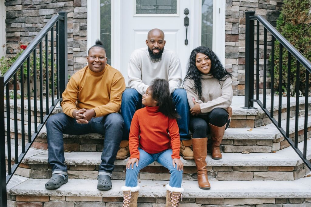 Happy black family sitting on stairs of modern house